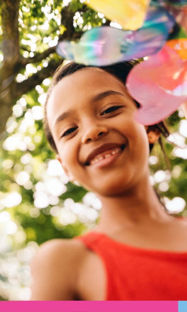 Young girl smiling holding a colorful pinwheel