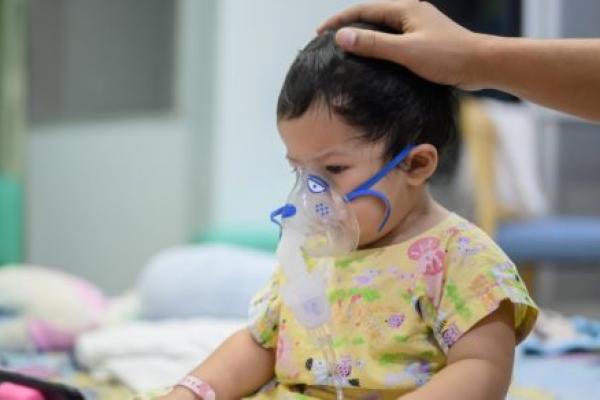 一个感染了呼吸道合胞病毒的婴儿在医院里她戴着一个含有止咳和流感药物的吸入器。