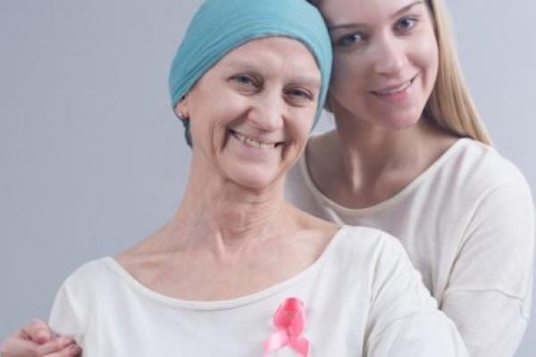 一位患有乳腺癌的妇女和她的女儿摆姿势。两人都在微笑。