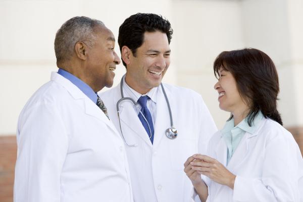站立在医院外面的三位医生互相聊天笑