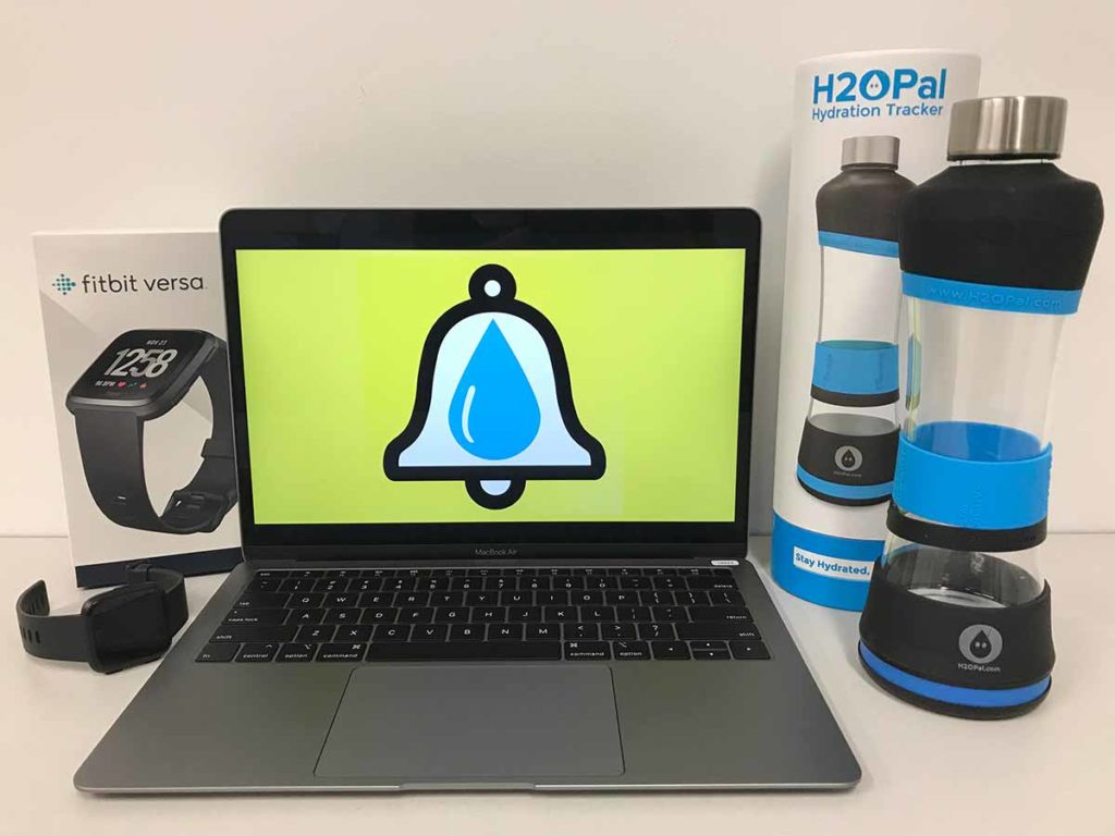 Fitbit Versa wrist watch and box, laptop with an image of a bell and a drop of water on the screen, and an H2OPal hydration tracker water bottle.