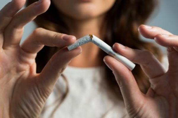 A woman snaps a cigarette in half.